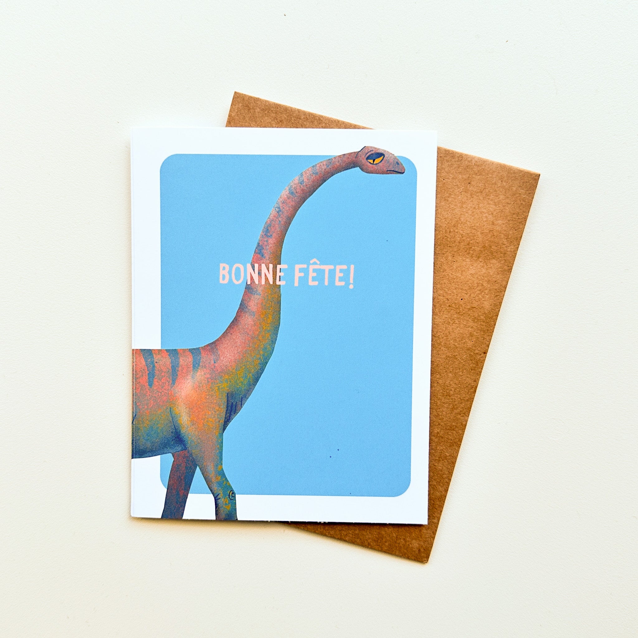 Illustration colorée d'un dinosaure sympathique sur une carte de voeux avec le message Bonne fête